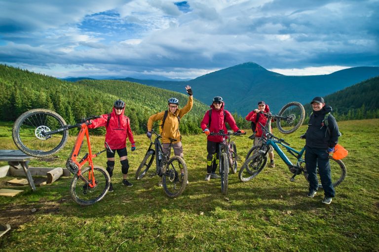 Group of cyclists men resting on the hill while riding electric bikes outdoors.